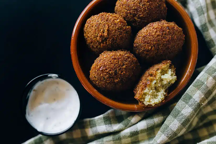 Image of bowl of falafel beside sauce